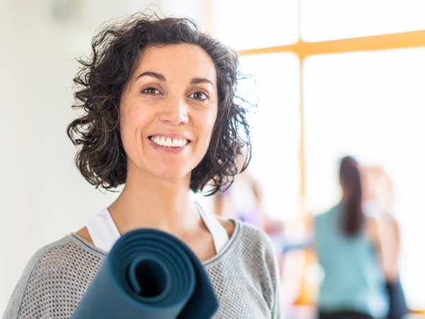 Woman smiling with yoga mat